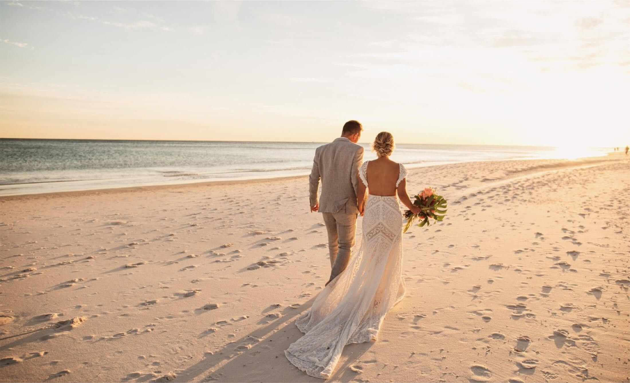 Groom and bride walking on beach