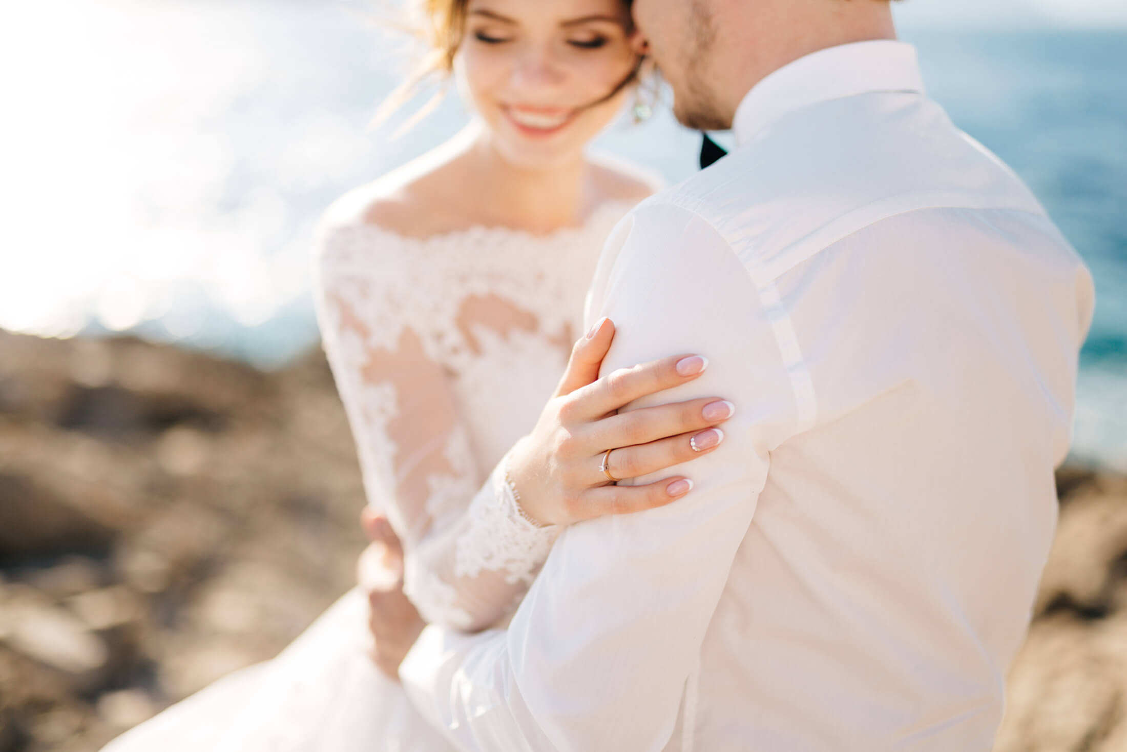 Bride and groom embracing on beach