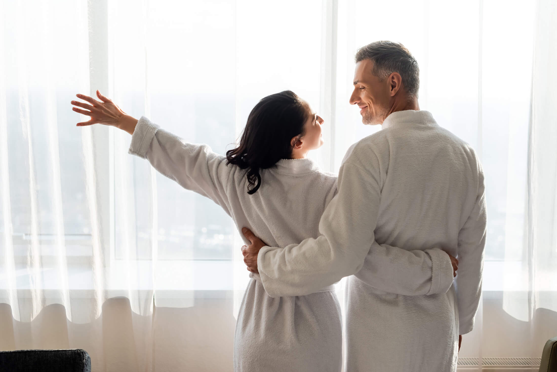 A couple standing in front of a window in robes at Pensacola Beach Resort